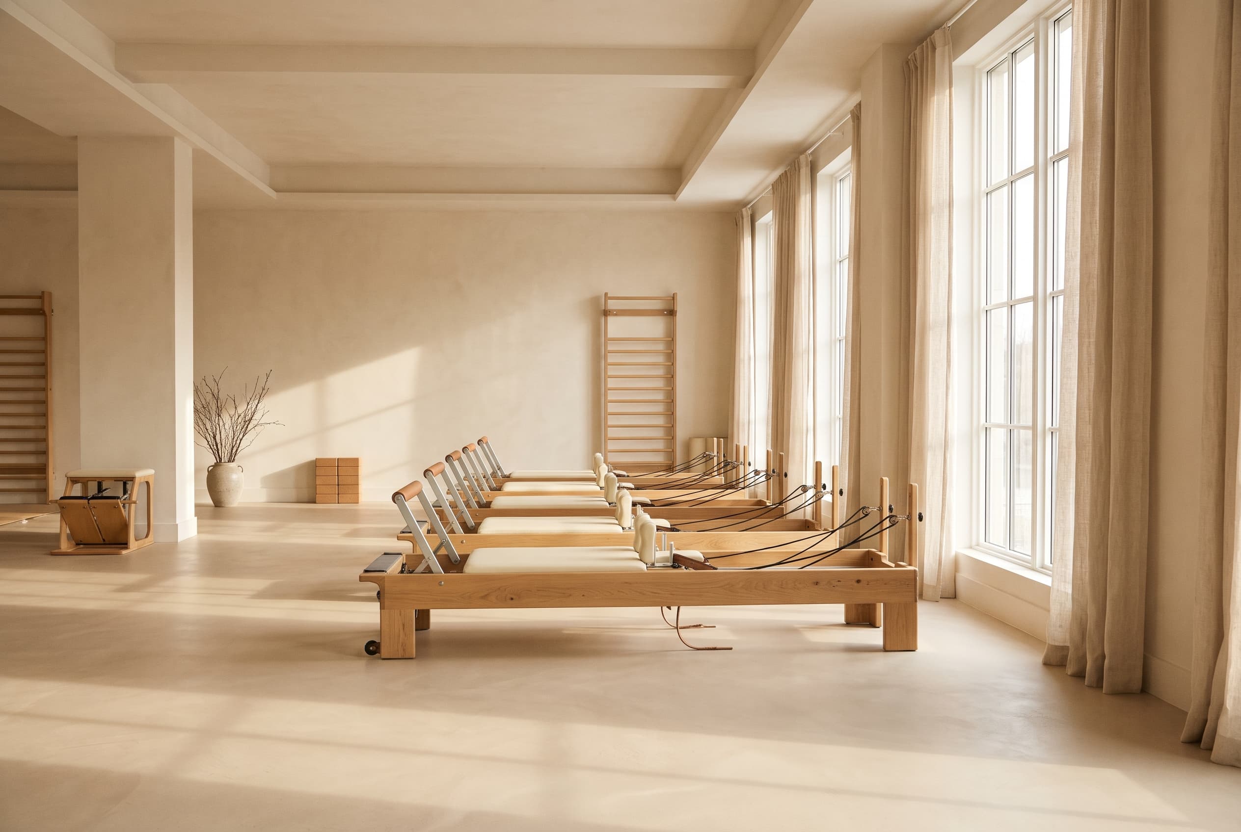 A calm Pilates studio in warm ivory and oak